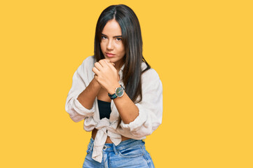 Young beautiful hispanic girl wearing casual clothes ready to fight with fist defense gesture, angry and upset face, afraid of problem