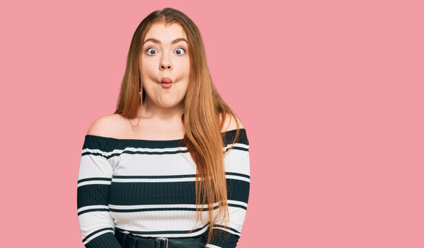 Young beautiful redhead woman wearing elegant clothes making fish face with lips, crazy and comical gesture. funny expression.