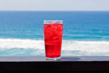 an ice cold red drink with a ocean view 