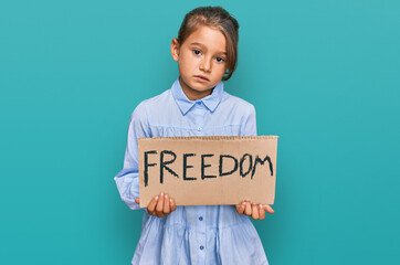 Little beautiful girl holding freedom banner thinking attitude and sober expression looking self confident