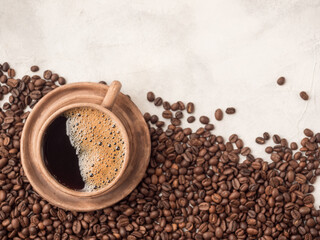 Roasted coffee beans lying on a white plate with a cup of coffee. Top view, place for tex, copy space.
