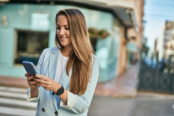 Young blonde businesswoman smiling happy using smartphone at the city.