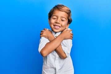 Adorable latin kid wearing casual clothes hugging oneself happy and positive, smiling confident....