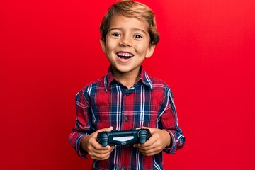 Adorable latin kid playing video game holding controller smiling and laughing hard out loud because...