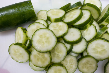 Heap of fresh sliced Cucumbers on cutting board.