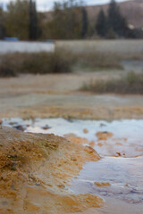 Hot mineral spring from a volcanic geyser, steam over streams