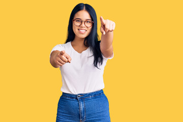 Obraz na płótnie Canvas Young beautiful asian girl wearing casual clothes and glasses pointing to you and the camera with fingers, smiling positive and cheerful