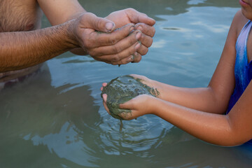 Healing mineral mud of volcanic origin, in a hot mineral spring, holding clay in the hands