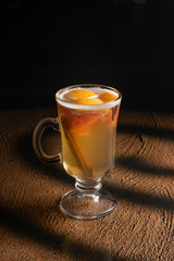 Hot fruit tea with orange, cinnamon and cloves in a clear glass