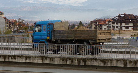 an old truck rides on a bridge over a mountain river in a mountainous area