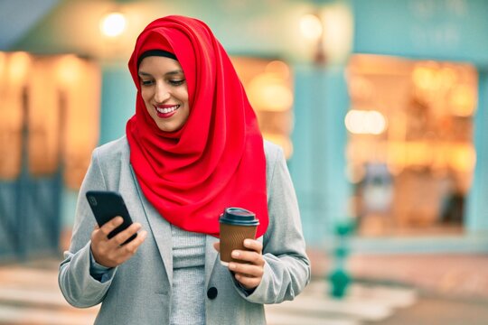Young arab businesswoman using smartphone and drinking coffee at the city.