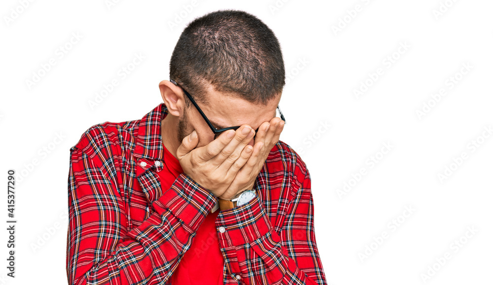 Wall mural hispanic young man wearing casual clothes with sad expression covering face with hands while crying.