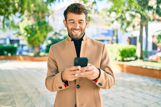 Handsome business man wearing elegant jacket using smartphone smiling happy outdoors