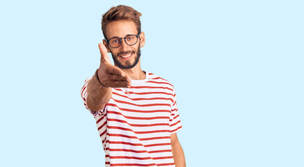 Handsome blond man with beard wearing casual clothes and glasses smiling friendly offering handshake as greeting and welcoming. successful business.