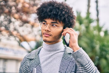 Young african american businessman with serious expression talking on the smartphone at the city.