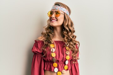 Young blonde girl wearing bohemian and hippie style looking away to side with smile on face,...