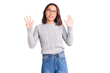 Young beautiful chinese girl wearing casual clothes showing and pointing up with fingers number...