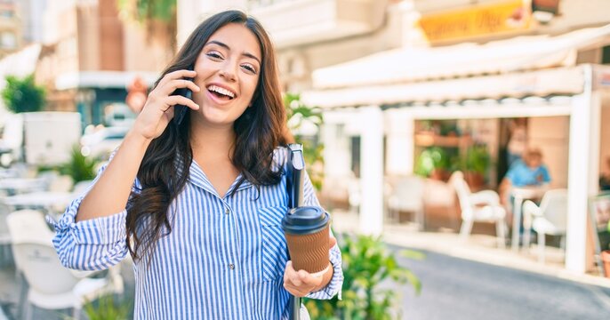 Young hispanic businesswoman talking on the smartphone and drinking take away coffee at the city.