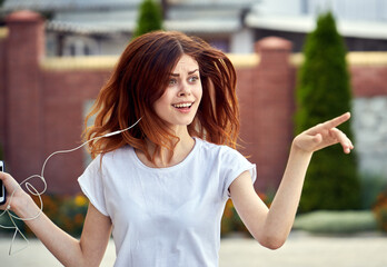 cheerful woman in headphones outdoors on the street walk