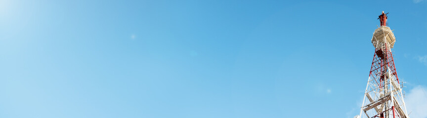 Telecommunication tower against the blue sky on a sunny day, cell antenna, transmitter. TV tower. Banner, on the left is an empty space for the text