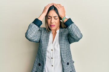 Young hispanic woman wearing business clothes suffering from headache desperate and stressed because pain and migraine. hands on head.