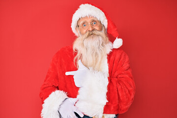 Old senior man with grey hair and long beard wearing traditional santa claus costume cheerful with a smile of face pointing with hand and finger up to the side with happy and natural expression