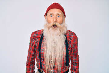 Old senior man with grey hair and long beard wearing hipster look with wool cap afraid and shocked with surprise and amazed expression, fear and excited face.