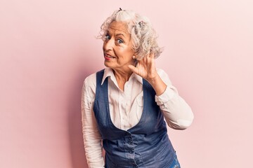 Senior grey-haired woman wearing casual clothes smiling with hand over ear listening and hearing to...
