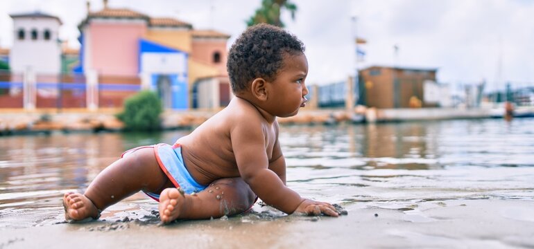 Adorable african american toddler sitting at the beach.