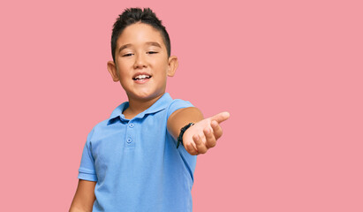 Little boy hispanic kid wearing casual clothes smiling cheerful offering palm hand giving assistance and acceptance.