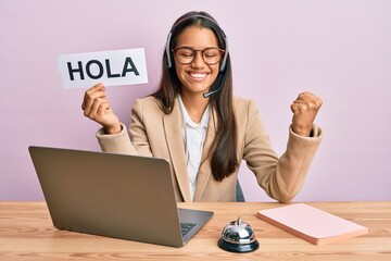 Beautiful hispanic woman wearing operator headset holding hola greenting screaming proud, celebrating victory and success very excited with raised arm © Krakenimages.com