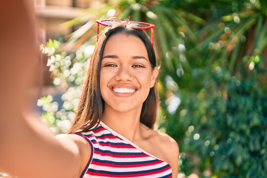 Young latin girl smiling happy making selfie by the camera at the city.