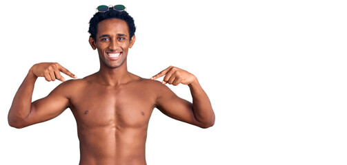 Fototapeta premium African handsome man wearing swimsuit and sunglasses looking confident with smile on face, pointing oneself with fingers proud and happy.