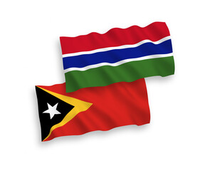 National vector fabric wave flags of East Timor and Republic of Gambia isolated on white background. 1 to 2 proportion.