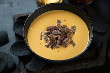 Bowl of bacon and cheese dipping sauce with black chips, studio shot, selective focus