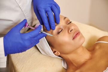 Beautician cosmetologist makes beauty injections into beautiful woman's face. Anti aging therapy...