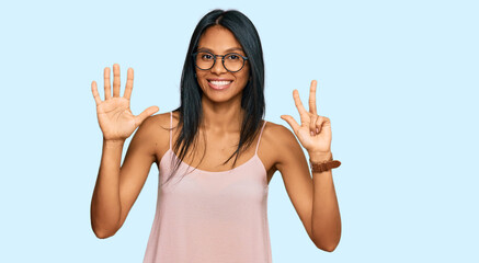 Fototapeta na wymiar Young african american woman wearing casual clothes and glasses showing and pointing up with fingers number eight while smiling confident and happy.