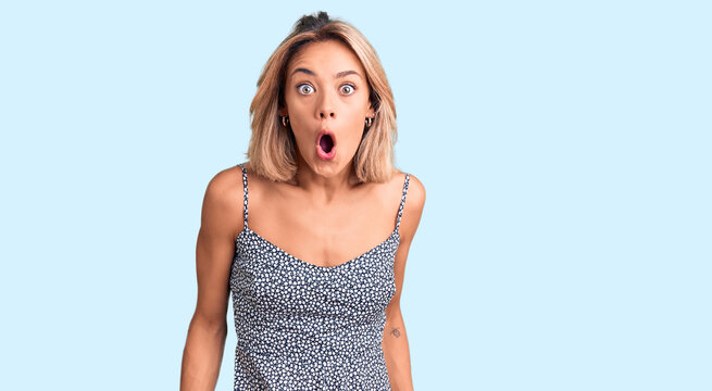Beautiful caucasian woman wearing summer dress afraid and shocked with surprise expression, fear and excited face.