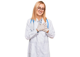 Beautiful caucasian woman wearing doctor uniform and stethoscope smiling with hands on chest with closed eyes and grateful gesture on face. health concept.