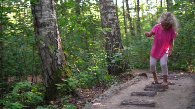 Barefoot girl child walk on healthy tree trunk bark and sand feet massage path