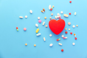 heart shape symbol and pills spilling on blue background 