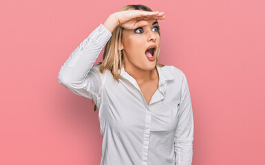 Young caucasian woman wearing casual clothes very happy and smiling looking far away with hand over...