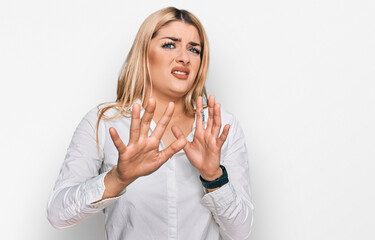 Young caucasian woman wearing casual clothes afraid and terrified with fear expression stop gesture with hands, shouting in shock. panic concept.