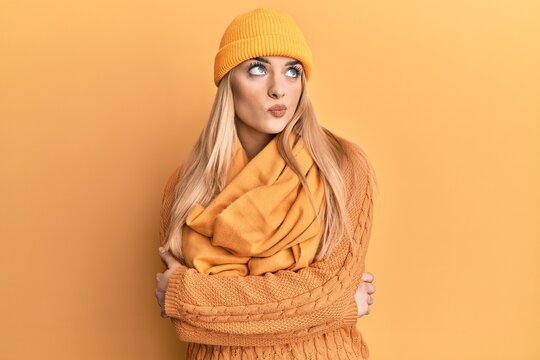 Young caucasian woman wearing wool winter sweater and cap smiling looking to the side and staring away thinking.