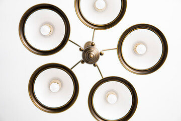 Bronze chandelier with five white glass lamp shades on a ceiling in a bedroom. Interior design.