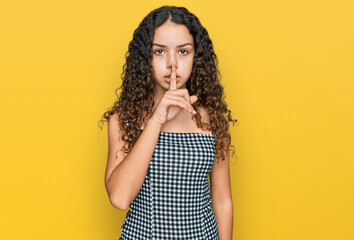 Teenager hispanic girl wearing casual clothes asking to be quiet with finger on lips. silence and secret concept.