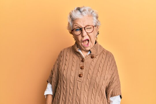 Senior grey-haired woman wearing casual clothes and glasses winking looking at the camera with sexy expression, cheerful and happy face.