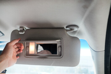 hand holding Car sun visor with illuminated mirror
