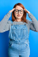 Beautiful redhead woman wearing casual clothes and glasses with hand on head, headache because stress. suffering migraine.