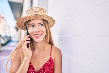 Young caucasian tourist girl smiling happy talking smartphone leaning on the wall.